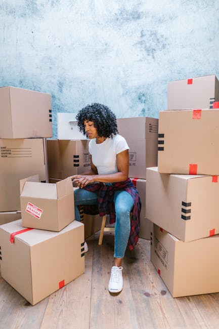 pexels-photo-7464430-7464430 A woman organizing cardboard boxes in a blue-toned room, preparing for a move.
